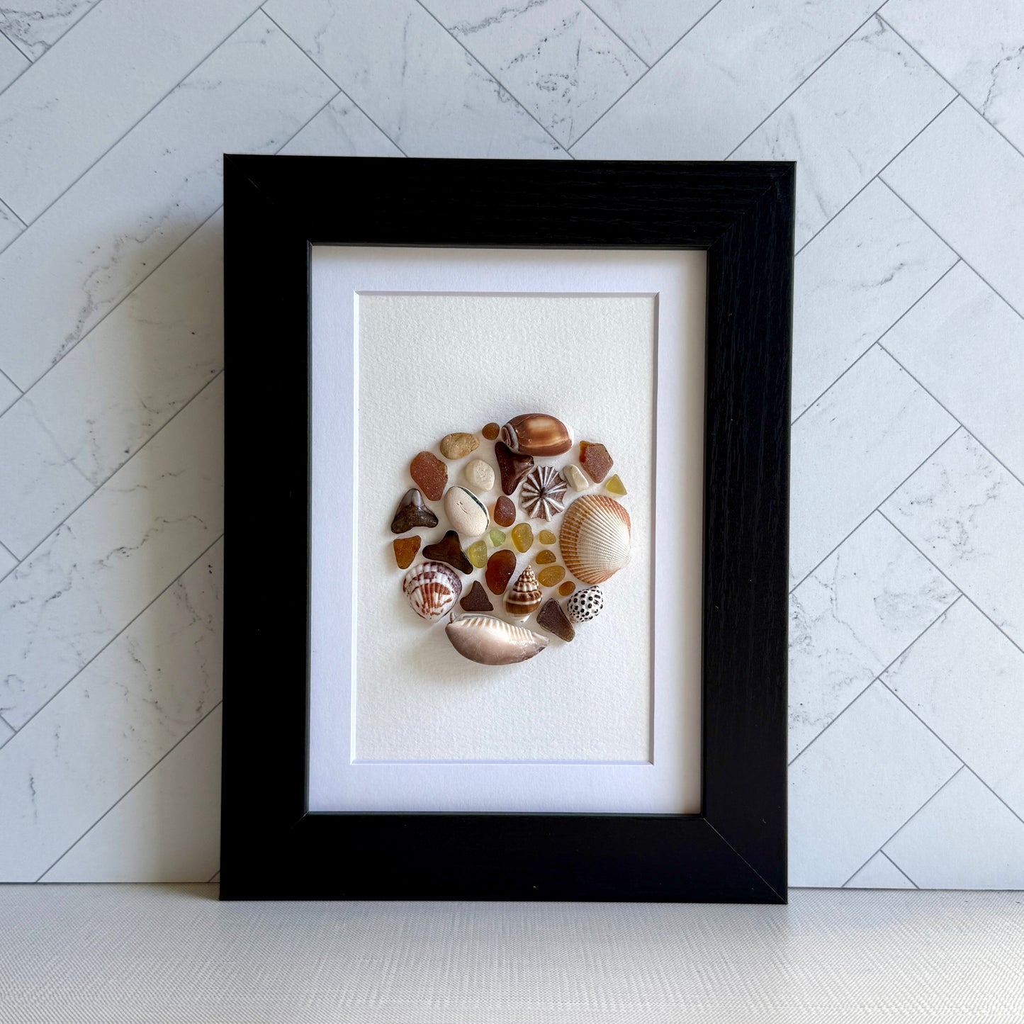 Framed artwork made of seashells on a white background