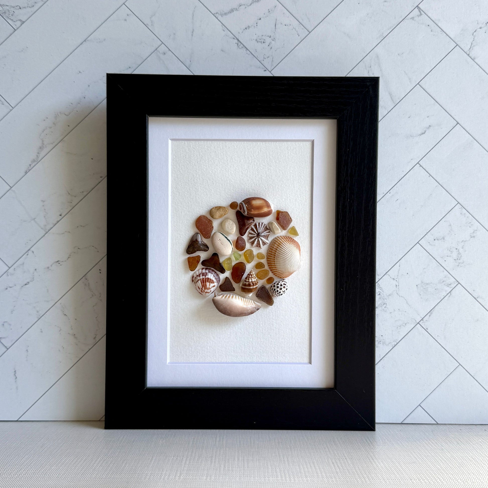 Framed artwork made of seashells on a white background