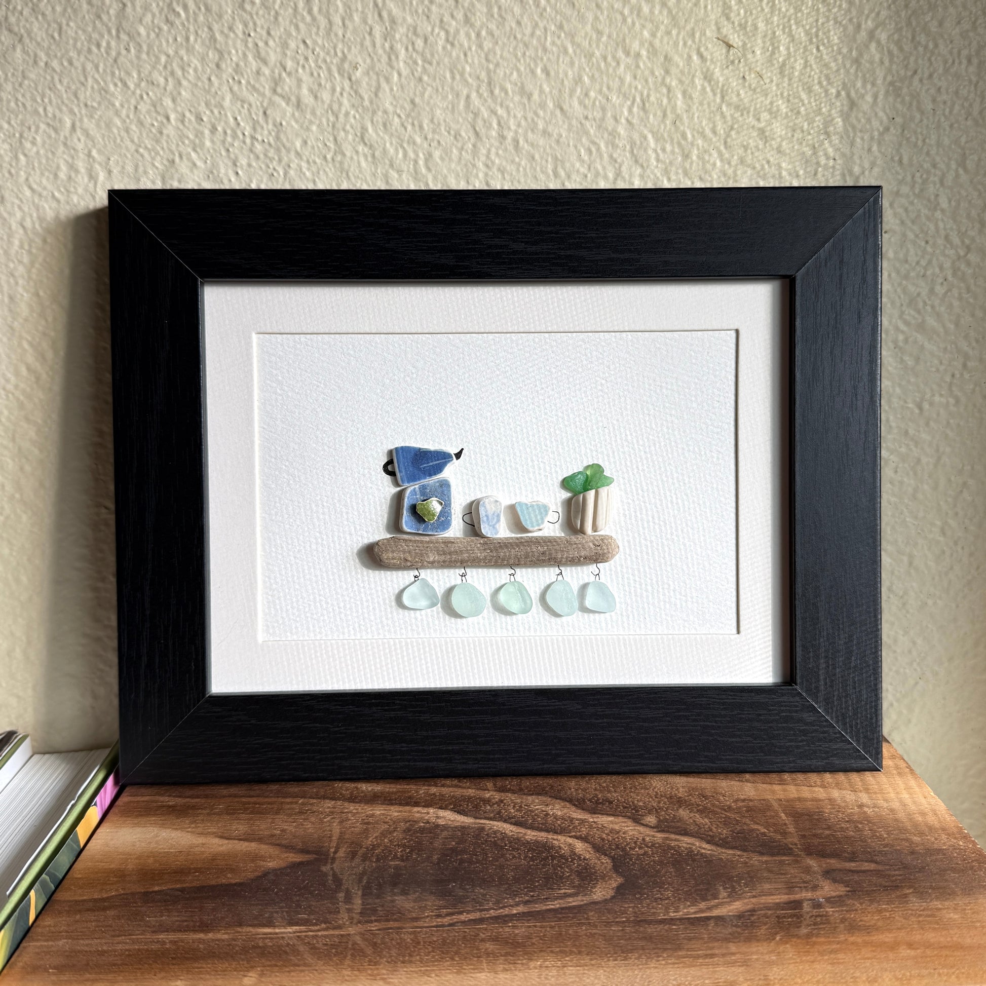 Handmade 5x7 framed sea glass and beach pottery coffee art with moka pot and mugs on driftwood shelf.