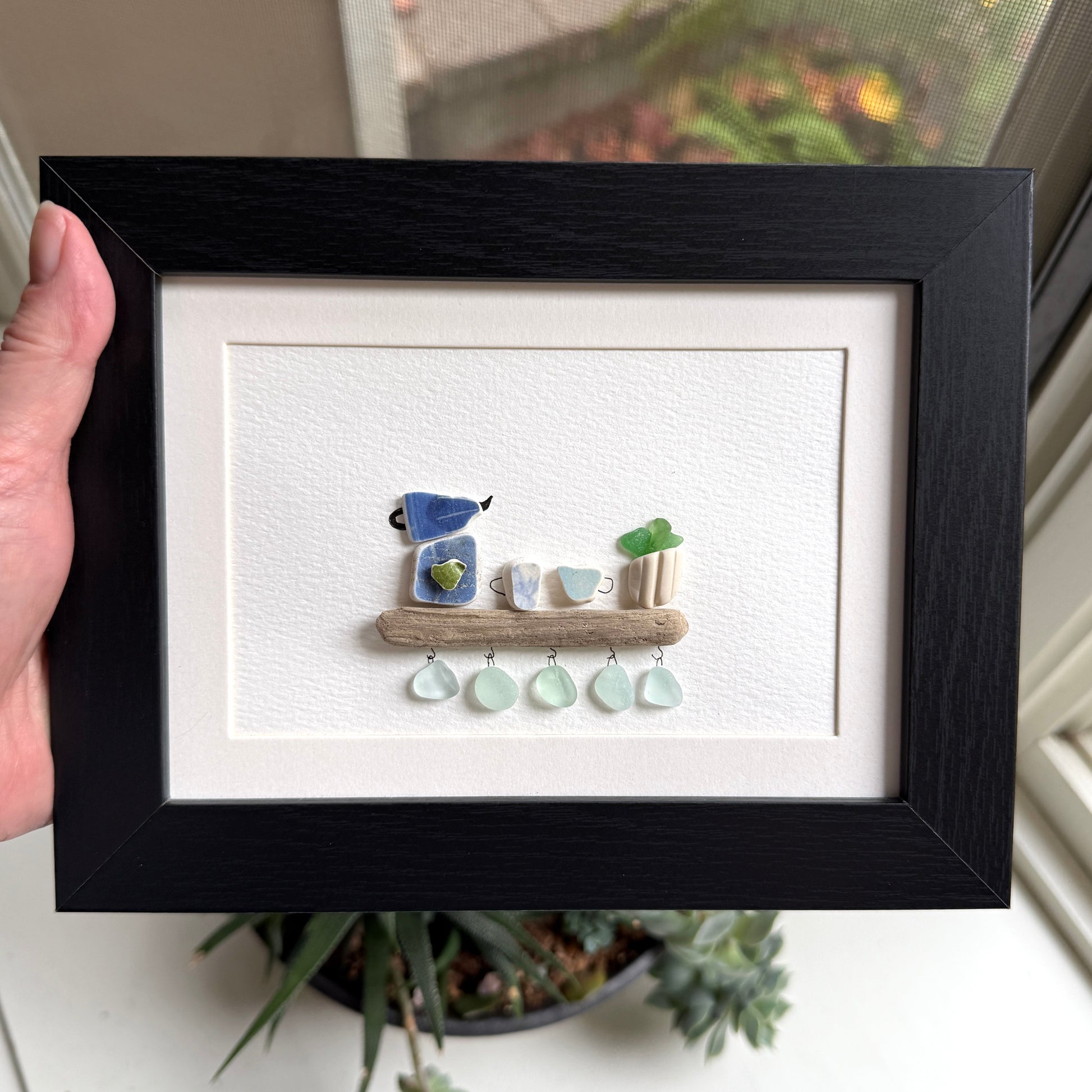 Handmade 5x7 framed sea glass and beach pottery coffee art with moka pot and mugs on driftwood shelf.