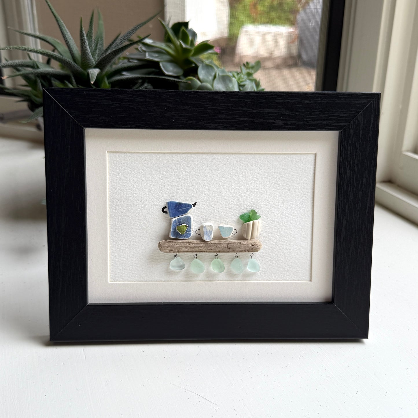 Handmade 5x7 framed sea glass and beach pottery coffee art with moka pot and mugs on driftwood shelf.