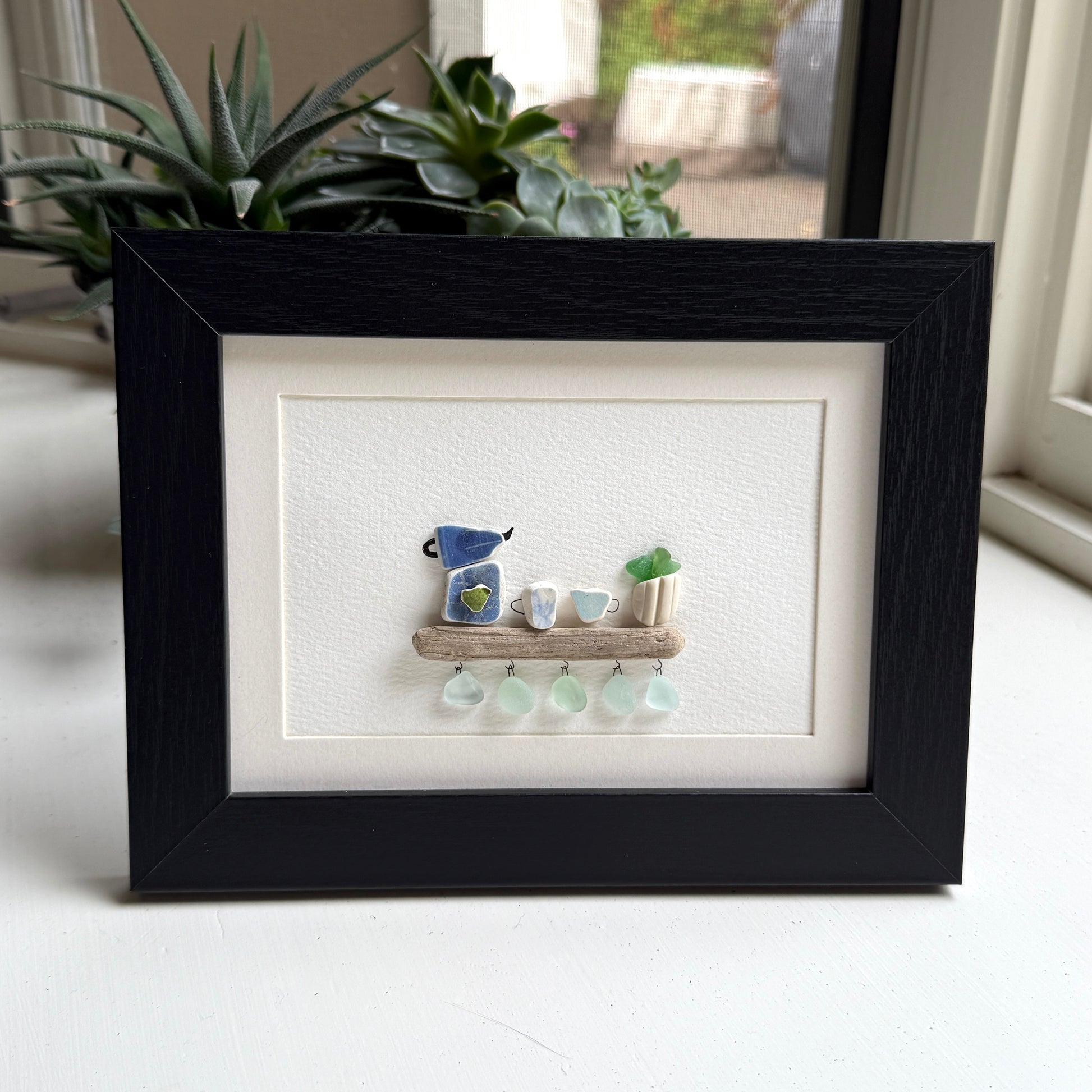 Handmade 5x7 framed sea glass and beach pottery coffee art with moka pot and mugs on driftwood shelf.