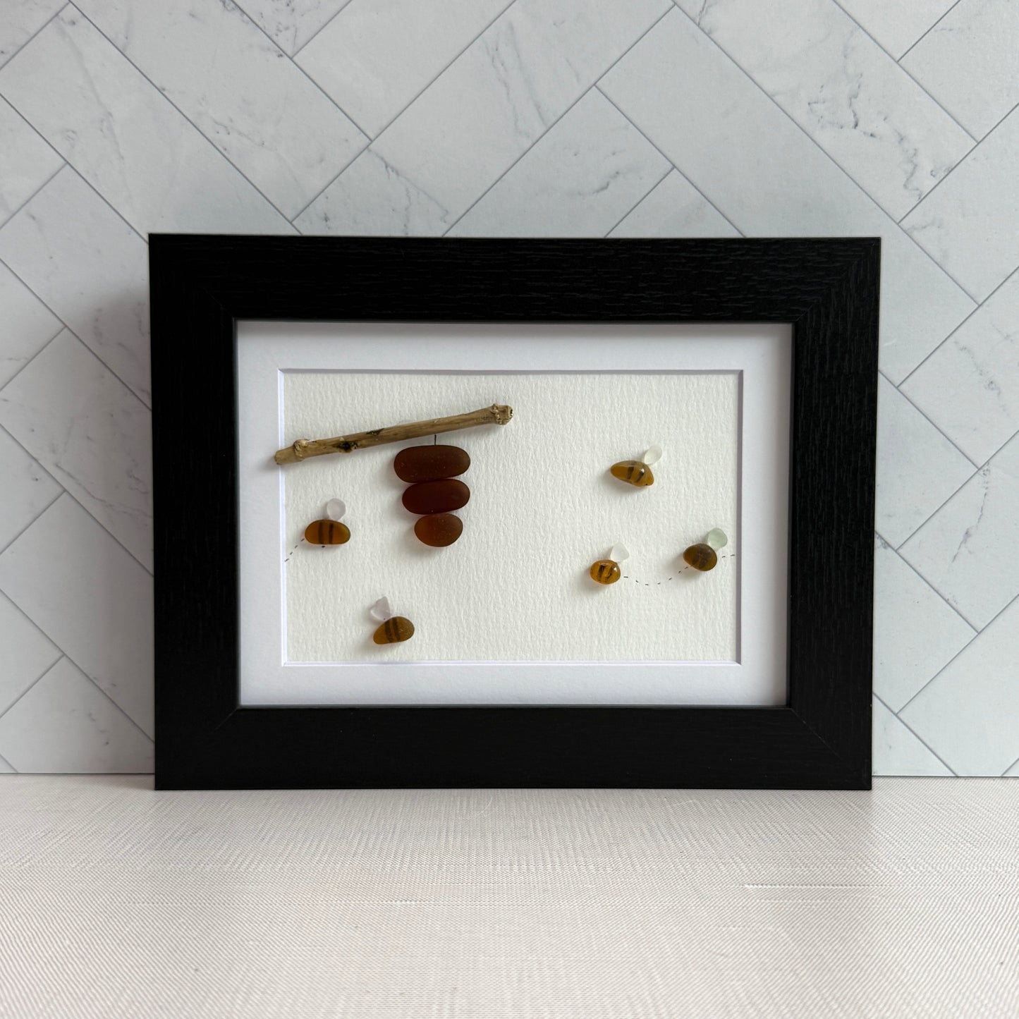 Amber and white sea glass bees with driftwood hive displayed on light background.