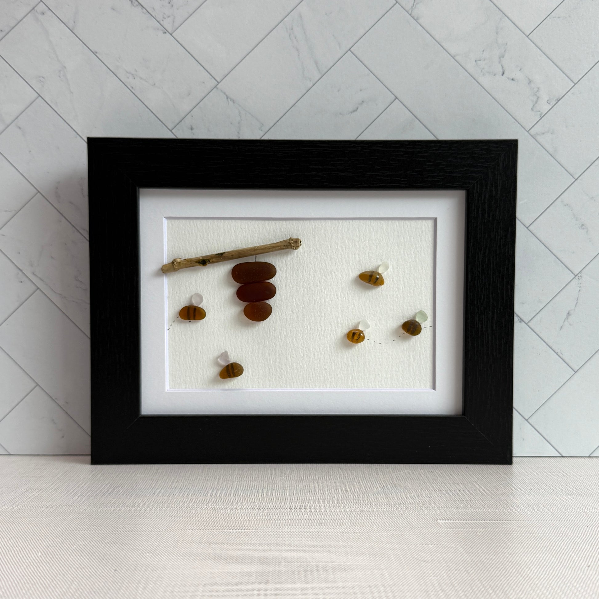 Amber and white sea glass bees with driftwood hive displayed on light background.