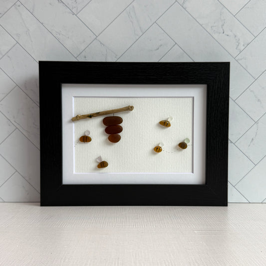 Amber and white sea glass bees with driftwood hive displayed on light background.