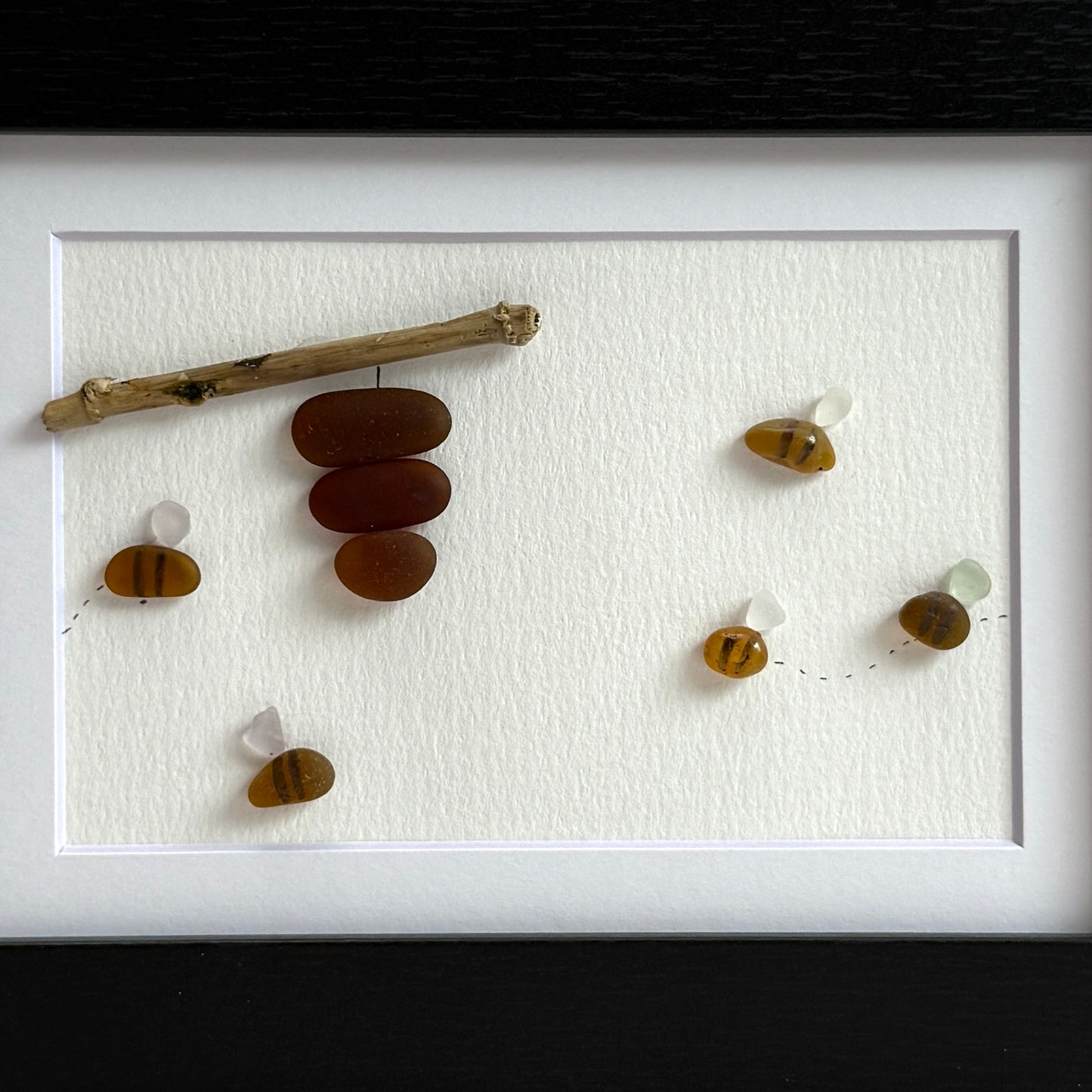 Amber and white sea glass bees with driftwood hive displayed on light background.