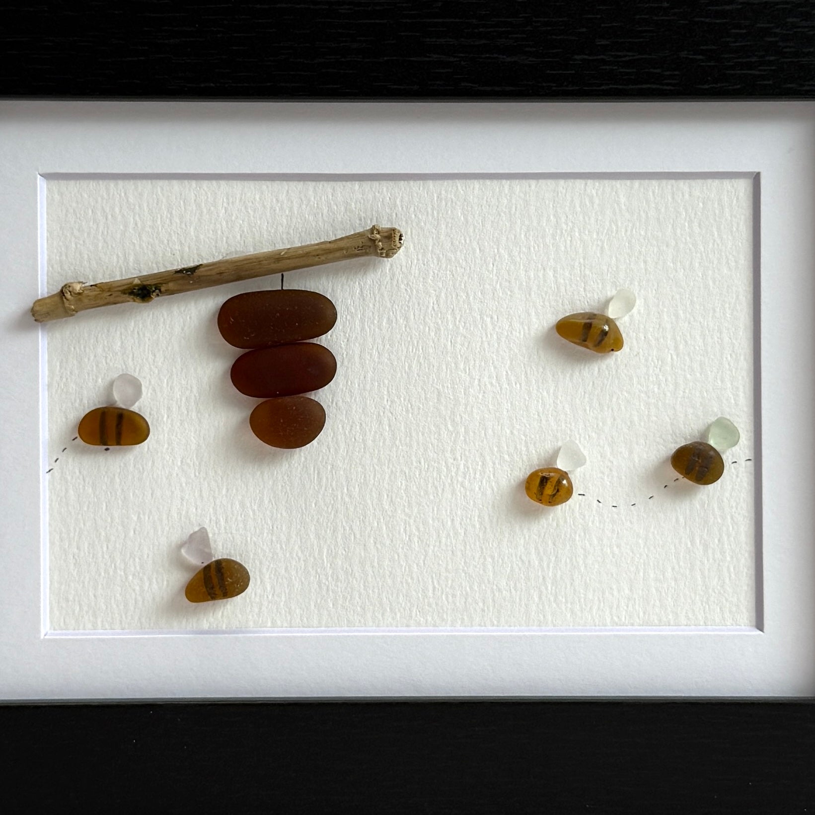Amber and white sea glass bees with driftwood hive displayed on light background.