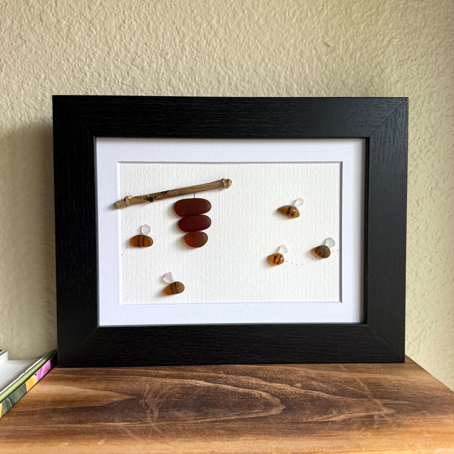 Amber and white sea glass bees with driftwood hive displayed on light background.
