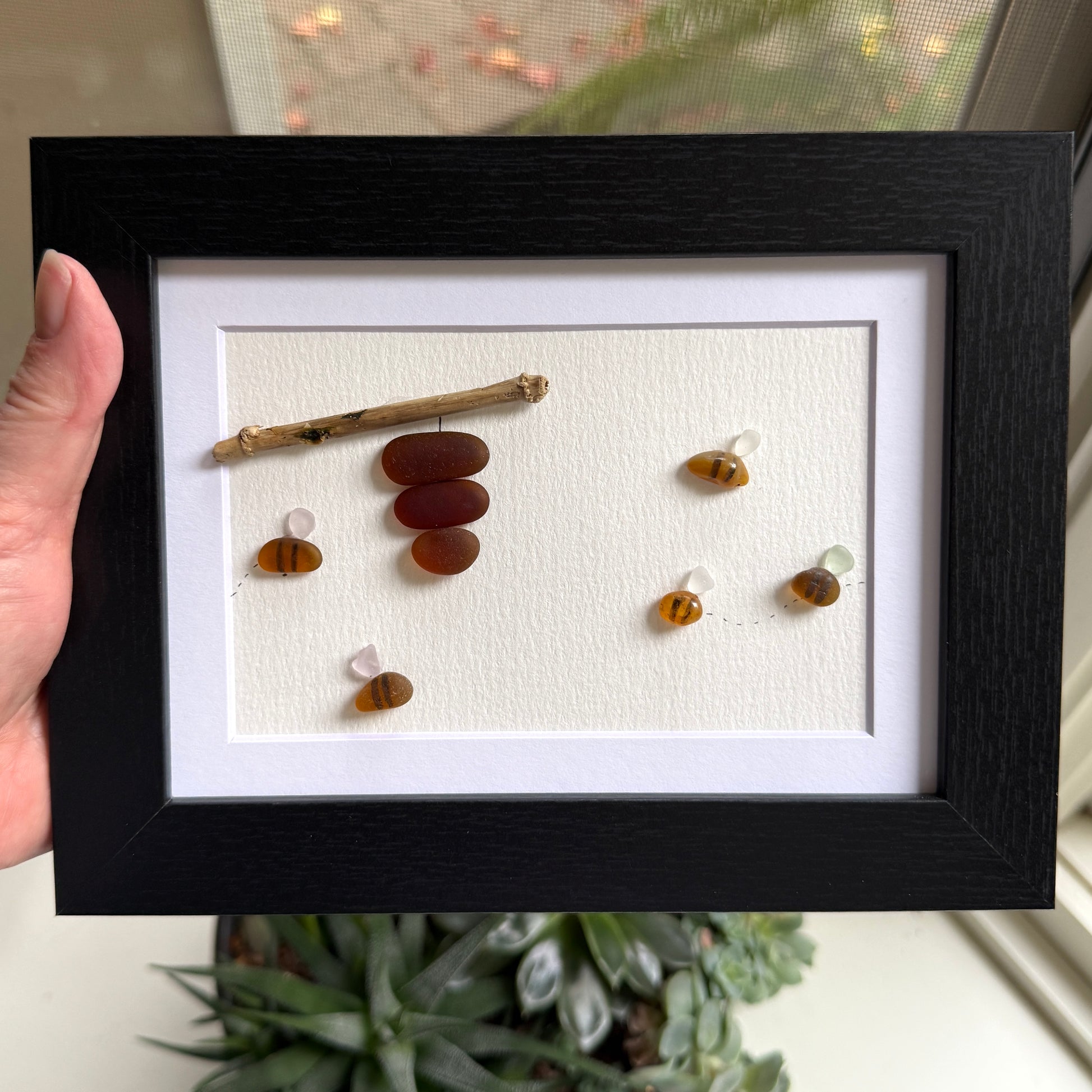 Amber and white sea glass bees with driftwood hive displayed on light background.