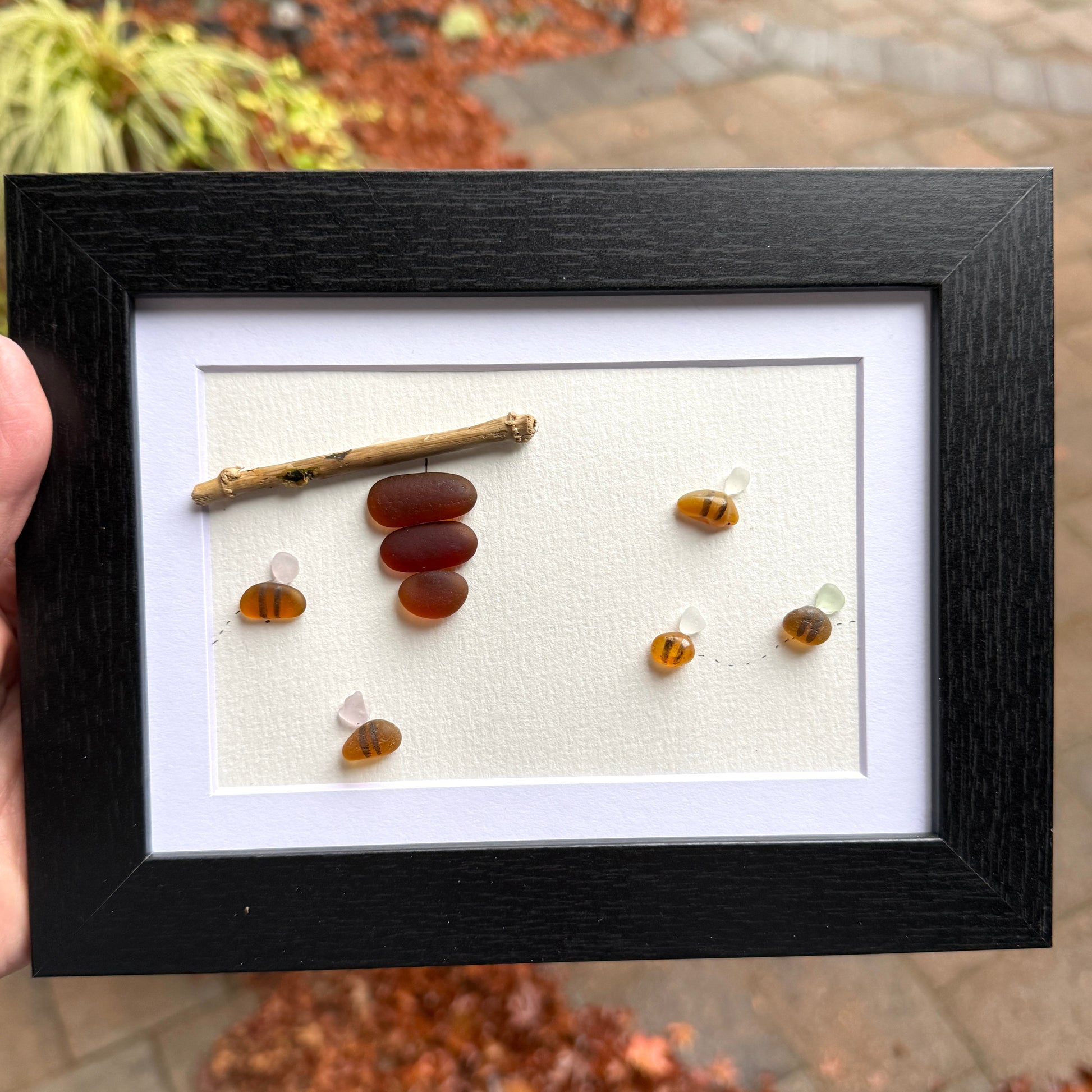 Amber and white sea glass bees with driftwood hive displayed on light background.