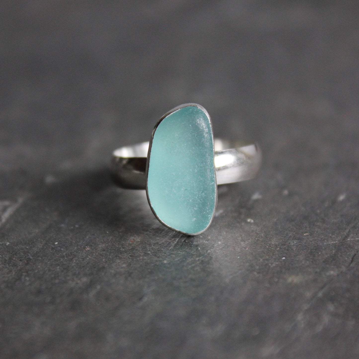 This ring has an aqua blue piece of sea glass in a fine and sterling silver bezel setting with a sturdy silver band.  Size 8 1/2