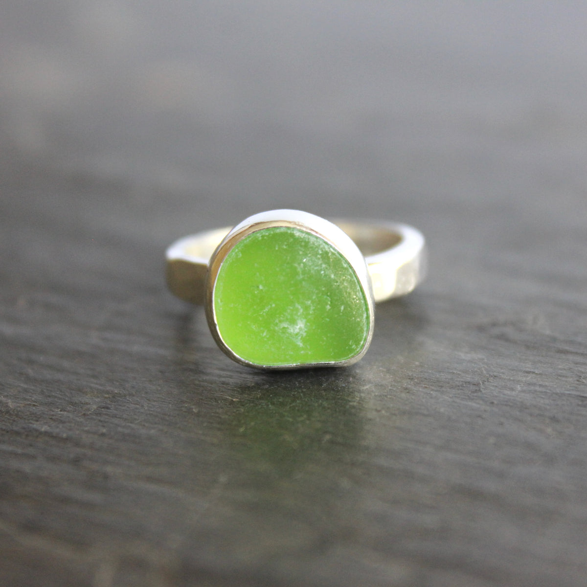 A ring made with a bright green piece of sea glass set in sterling silver. Size 8.5