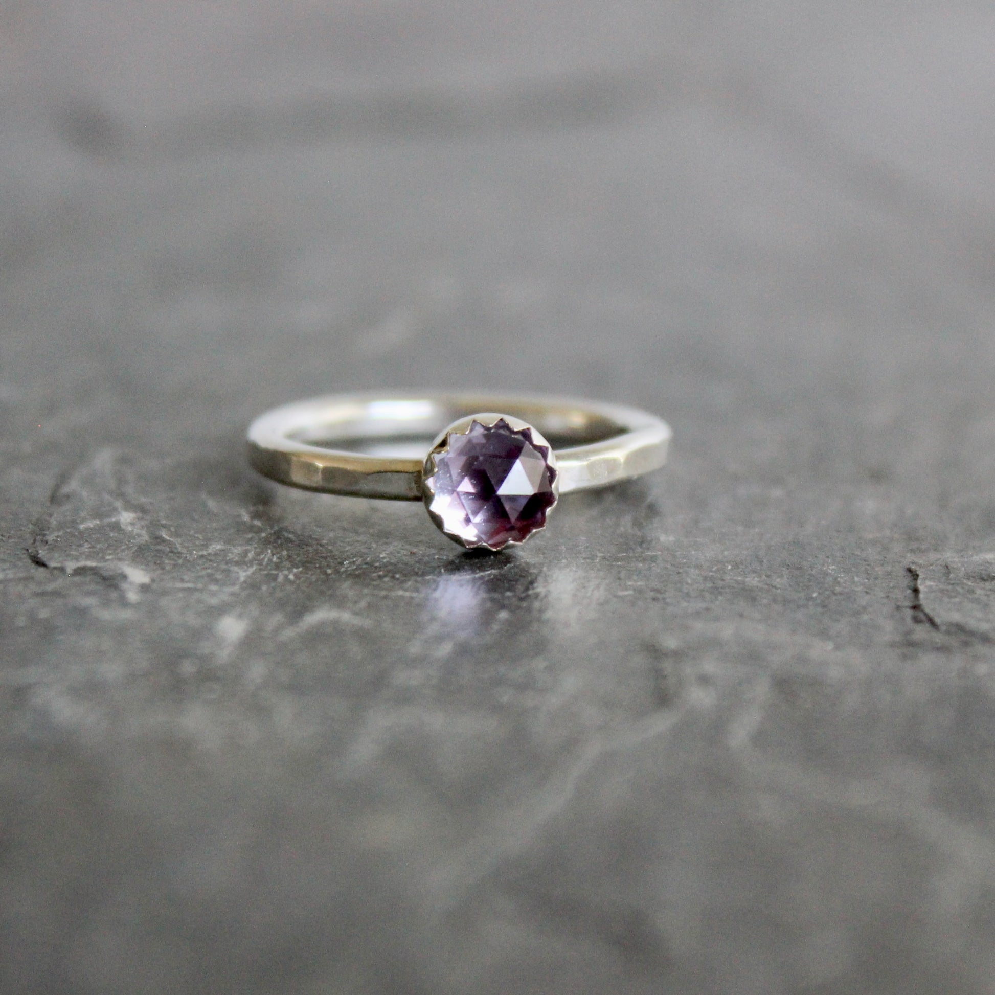 Silver ring with a lab-created alexandrite on a gray surface