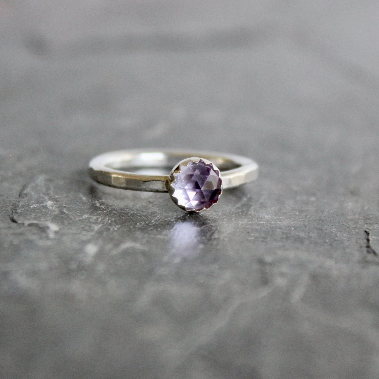 Silver ring with a lab-created alexandrite on a gray surface