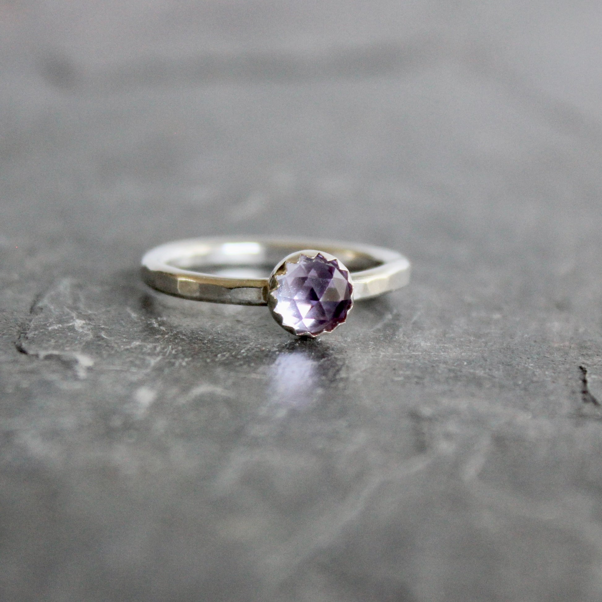 Silver ring with a lab-created alexandrite on a gray surface