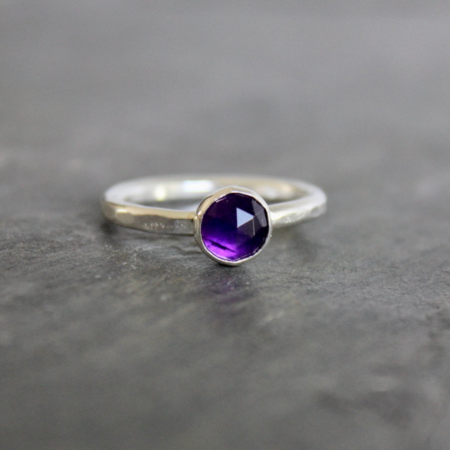 Silver ring with a purple amethyst  gemstone on a gray background