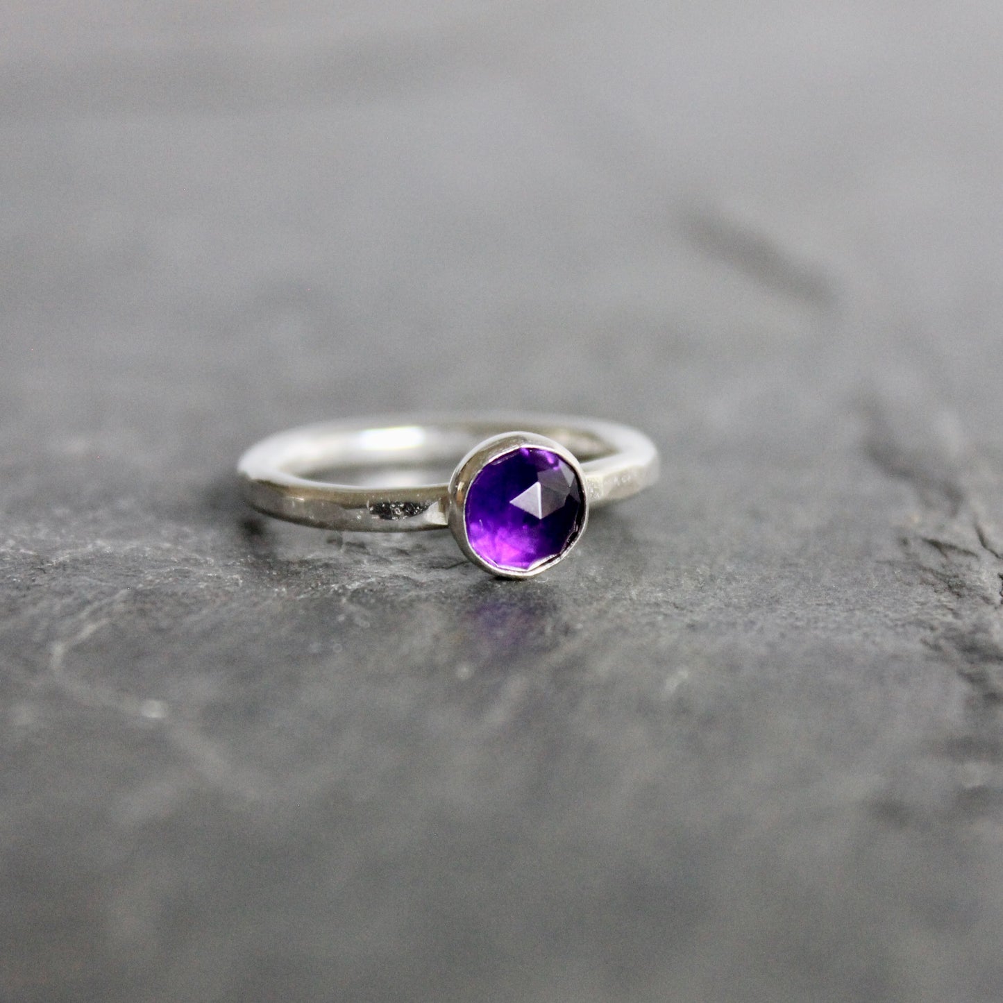 Silver ring with a purple amethyst  gemstone on a gray background