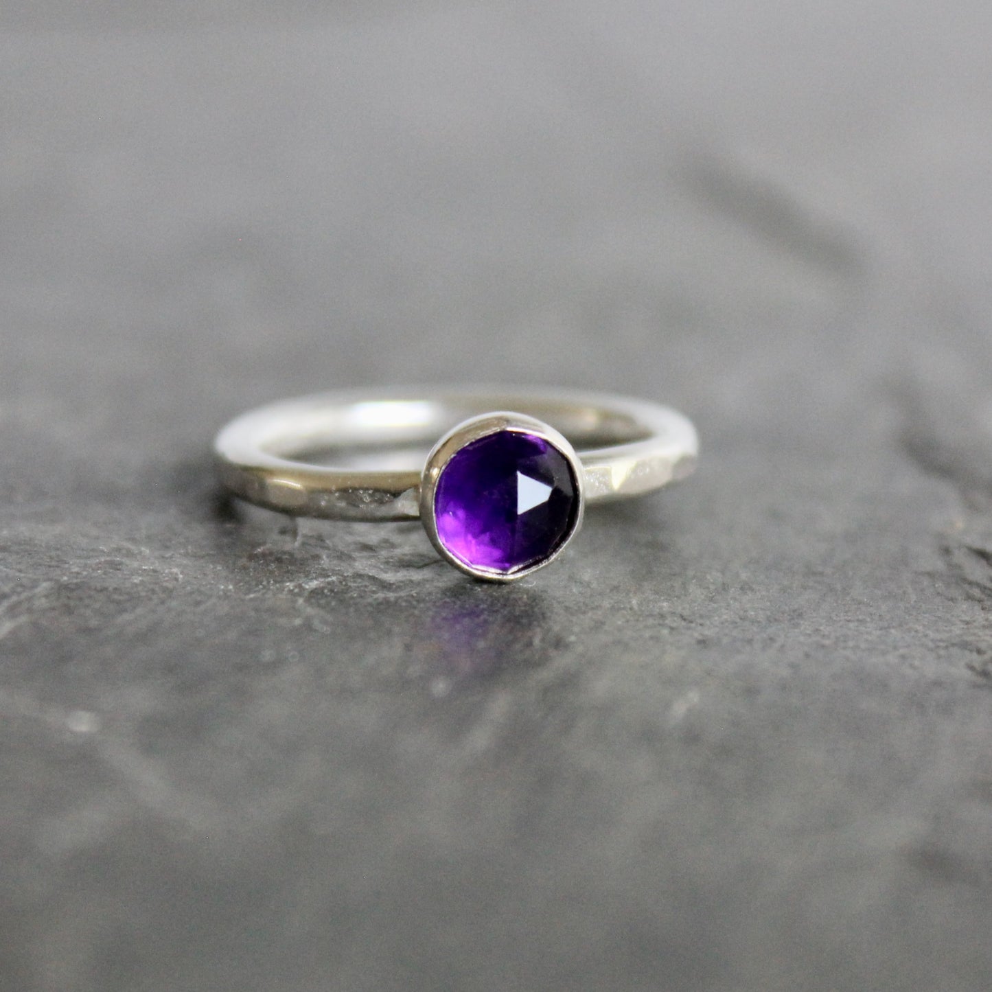 Silver ring with a purple amethyst  gemstone on a gray background