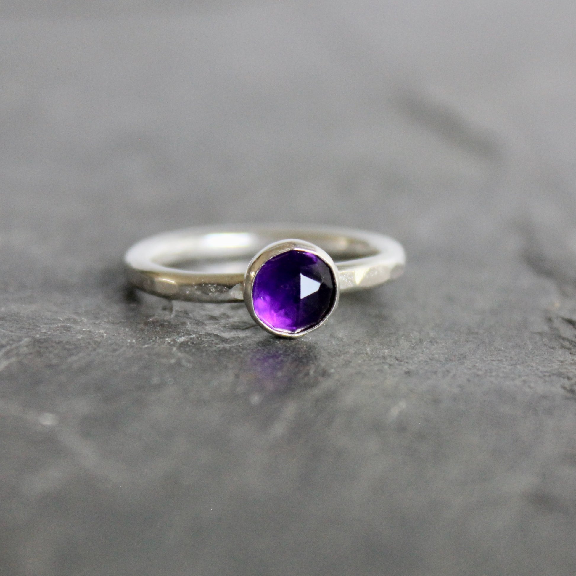 Silver ring with a purple amethyst  gemstone on a gray background
