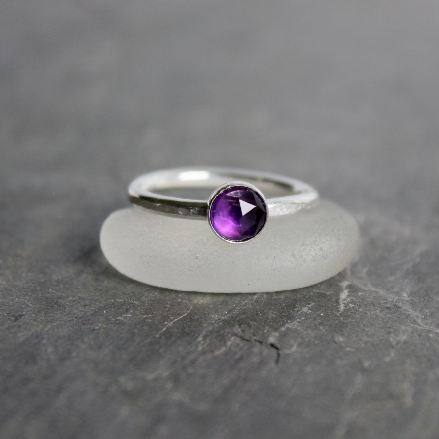Silver ring with a purple amethyst  gemstone on a gray background