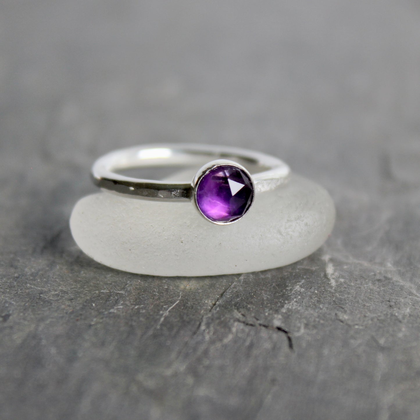 Silver ring with a purple amethyst  gemstone on a gray background