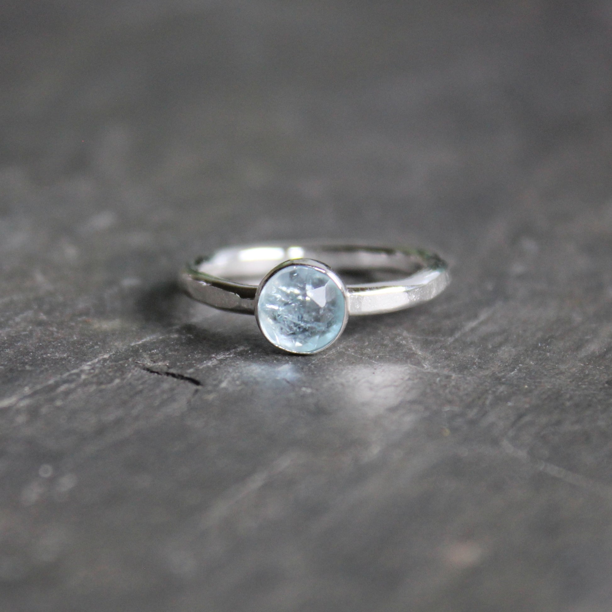 Silver ring with a aquamarine gemstone on a dark stone surface
