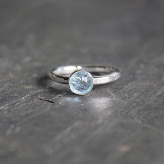 Silver ring with a aquamarine gemstone on a dark stone surface