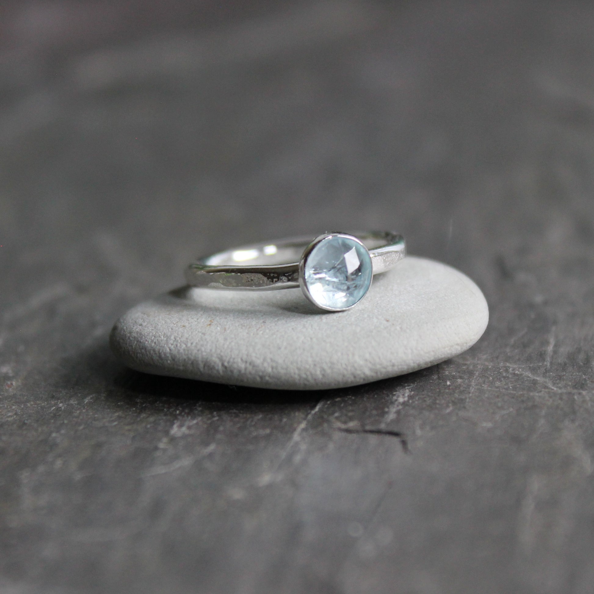 Silver ring with a aquamarine gemstone on a dark stone surface