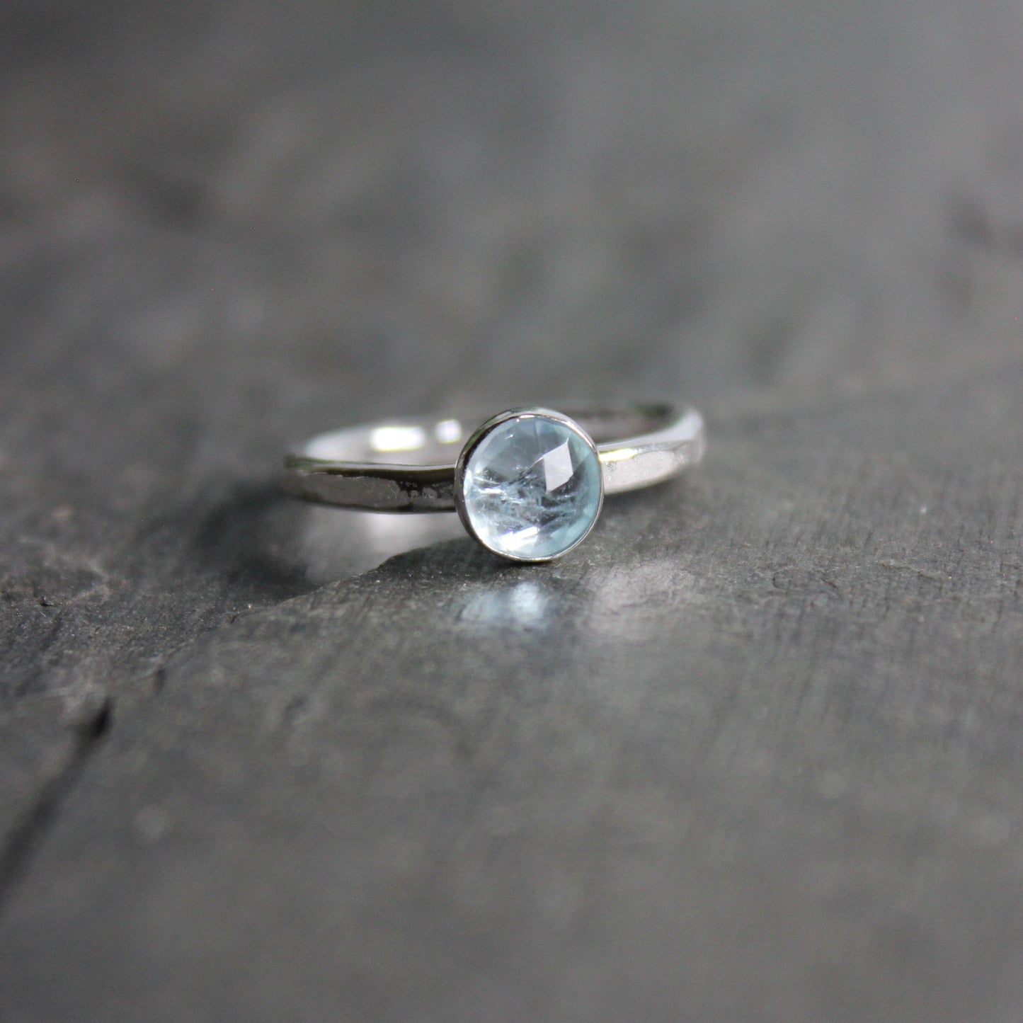 Silver ring with a aquamarine gemstone on a dark stone surface