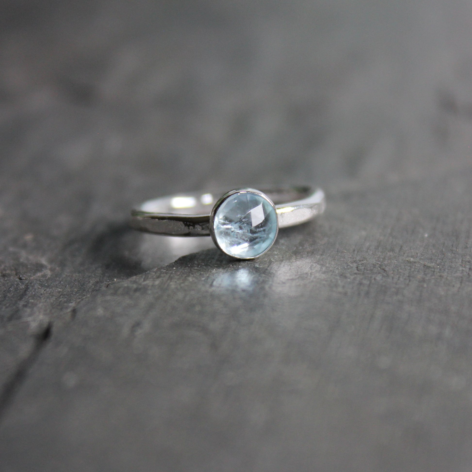 Silver ring with a aquamarine gemstone on a dark stone surface