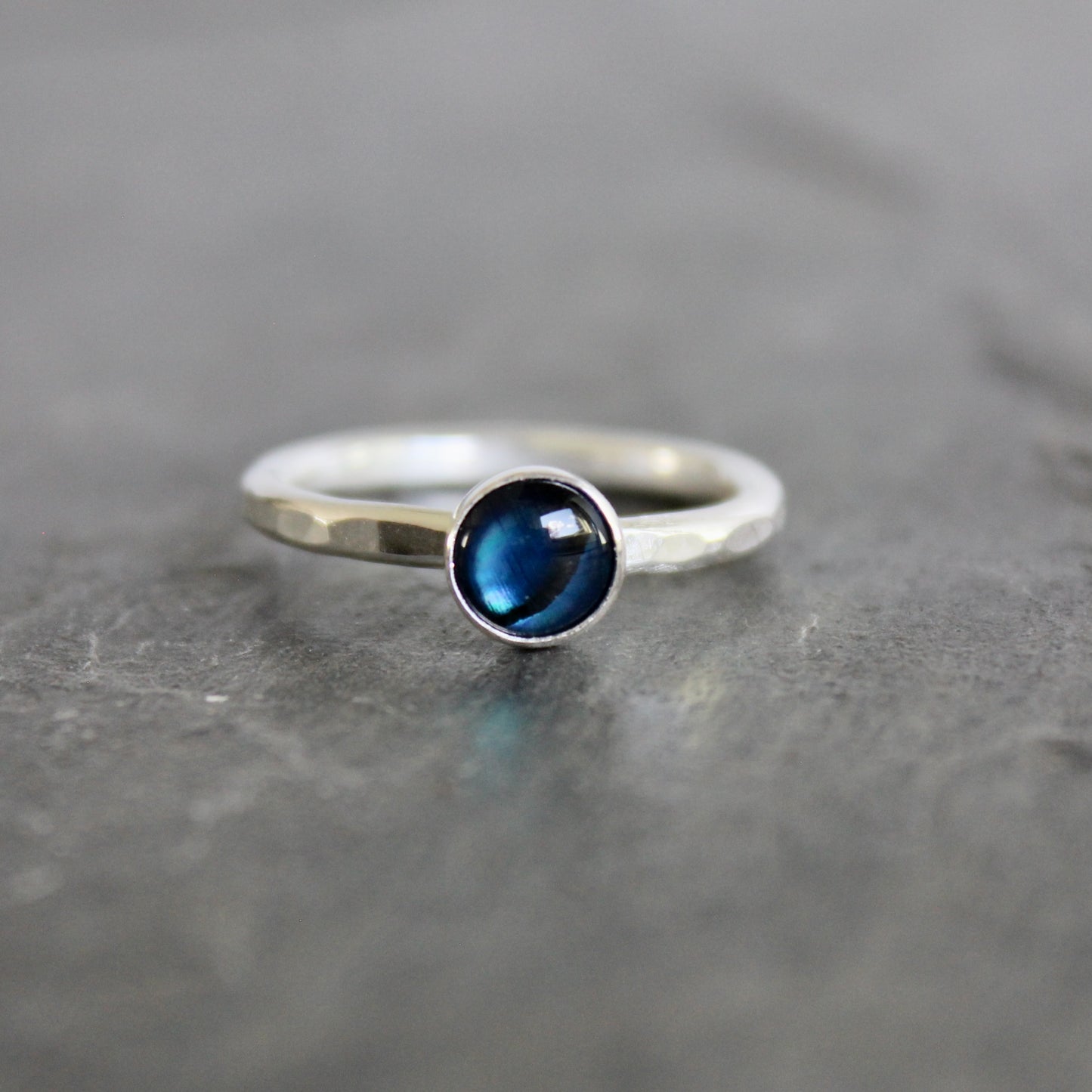 Silver ring with a blue gemstone on a gray surface