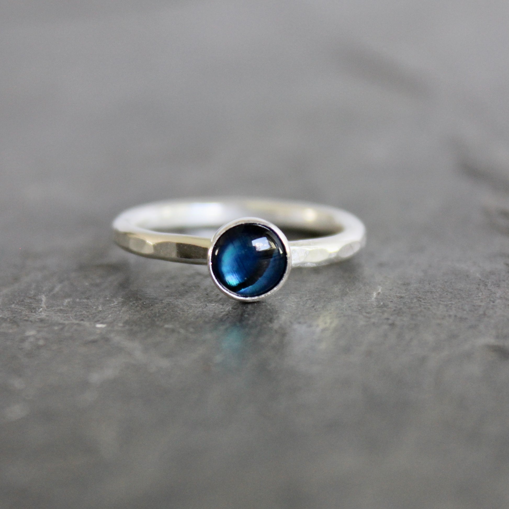 Silver ring with a blue gemstone on a gray surface