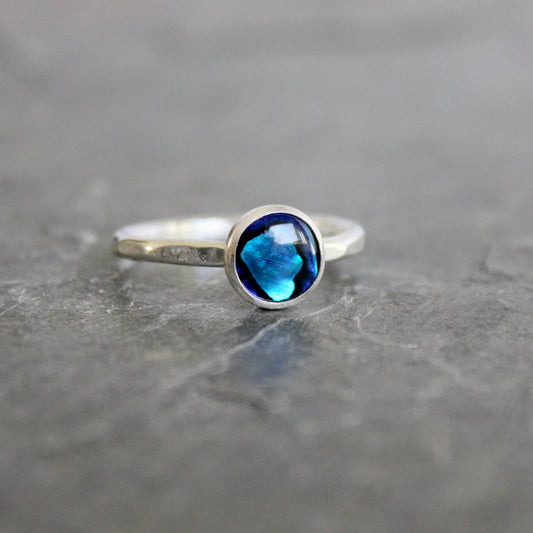 Silver ring with a blue abalone gemstone on a gray surface