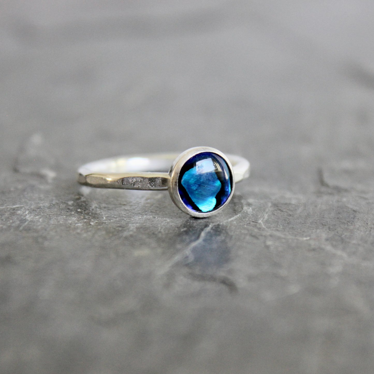 Silver ring with a blue abalone gemstone on a gray surface