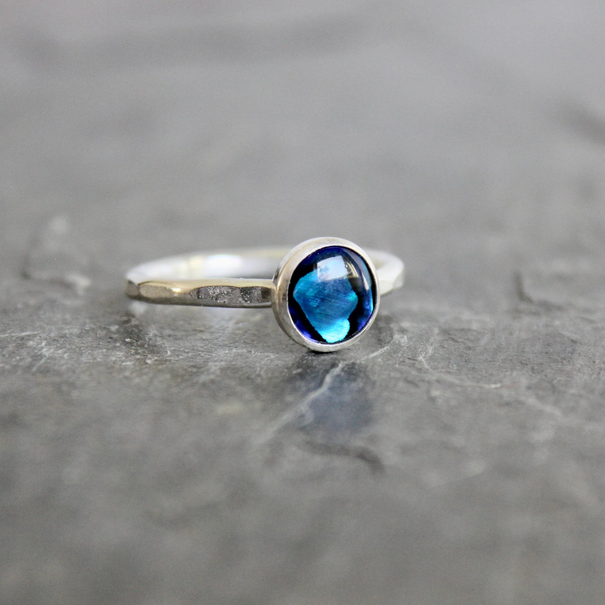 Silver ring with a blue abalone gemstone on a gray surface