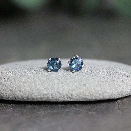 These stud earrings have 4mm round faceted lab created blue zircon set in sterling silver 4-prong earring settings with eariring backs. 