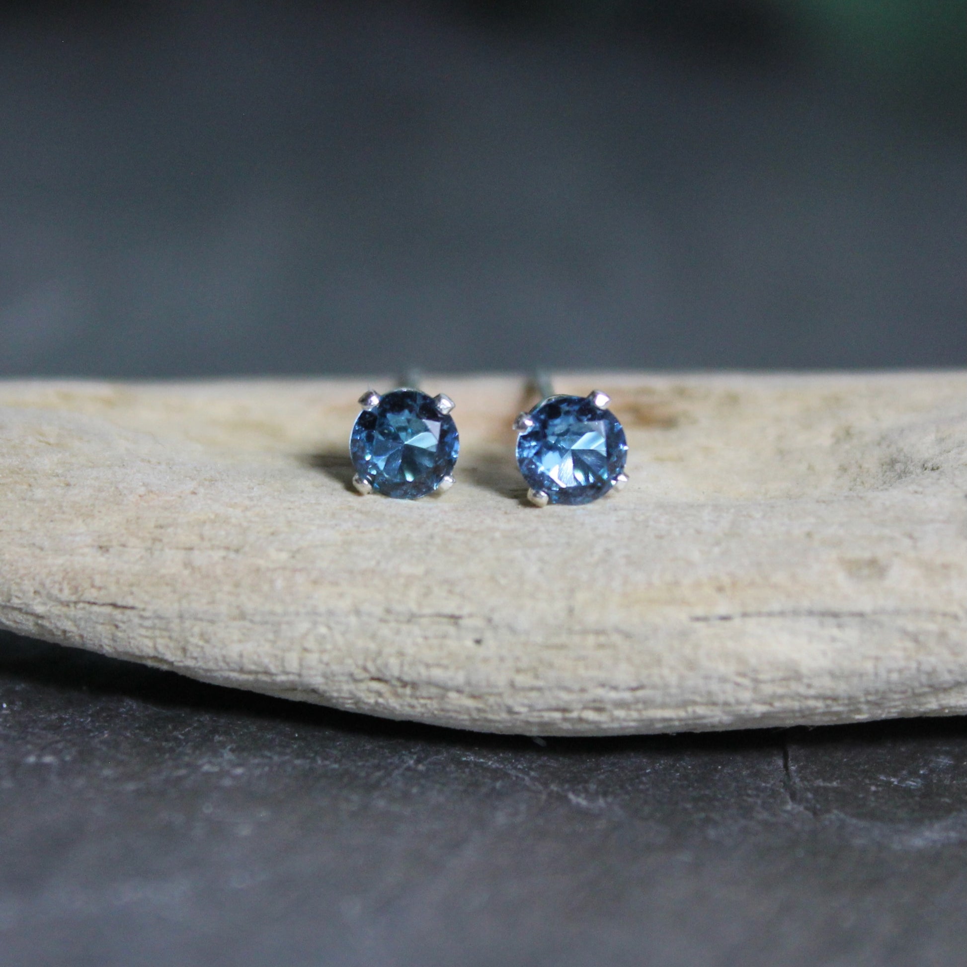 These stud earrings have 4mm round faceted lab created blue zircon set in sterling silver 4-prong earring settings with eariring backs. 