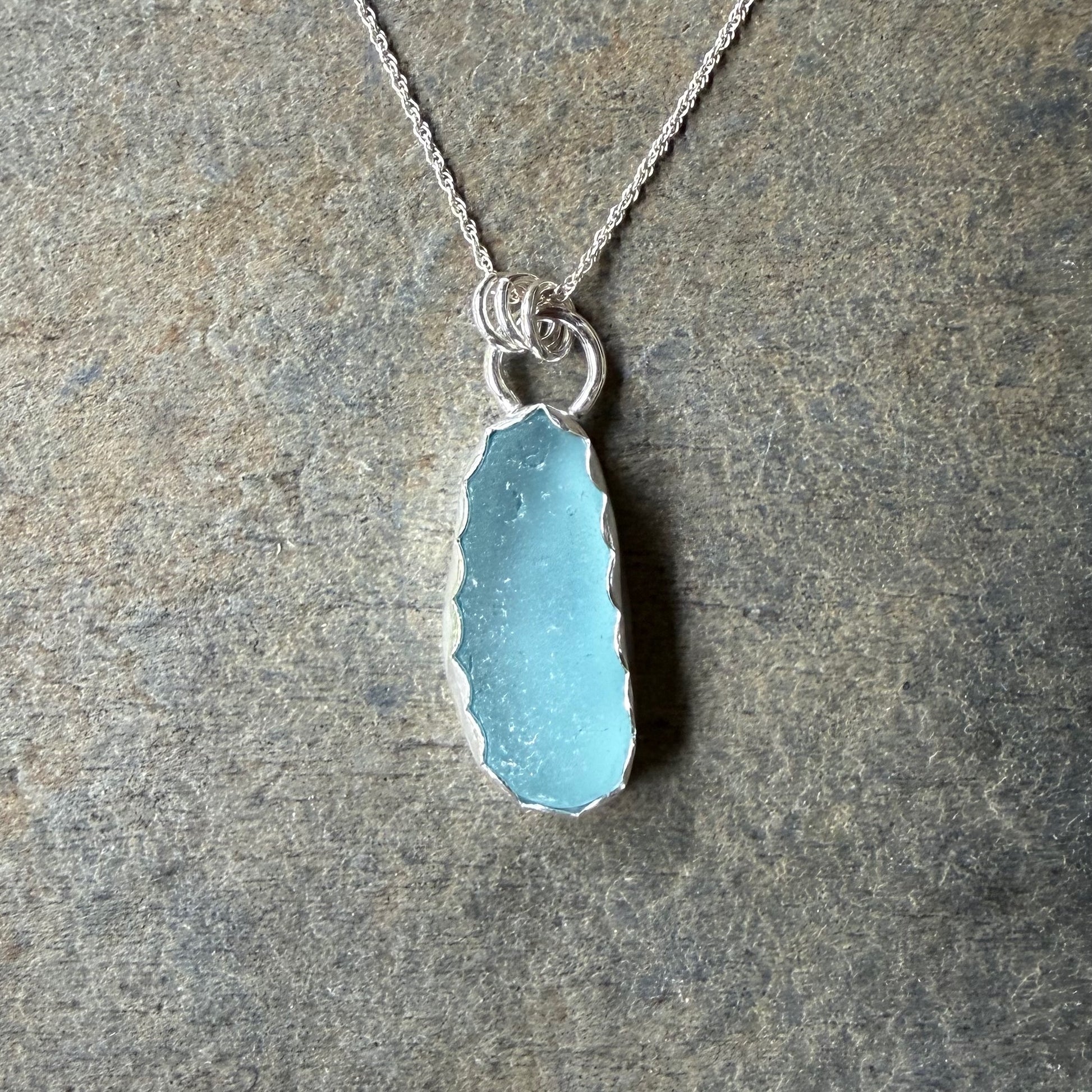 Necklace with a blue sea glass on a stone surface