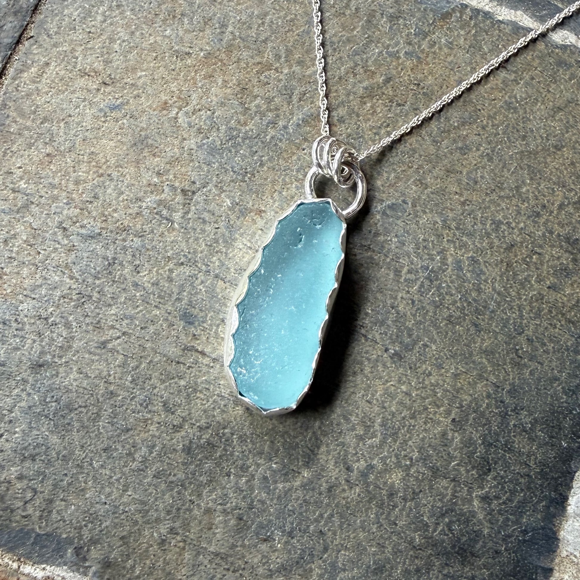 Necklace with a blue sea glass on a stone surface