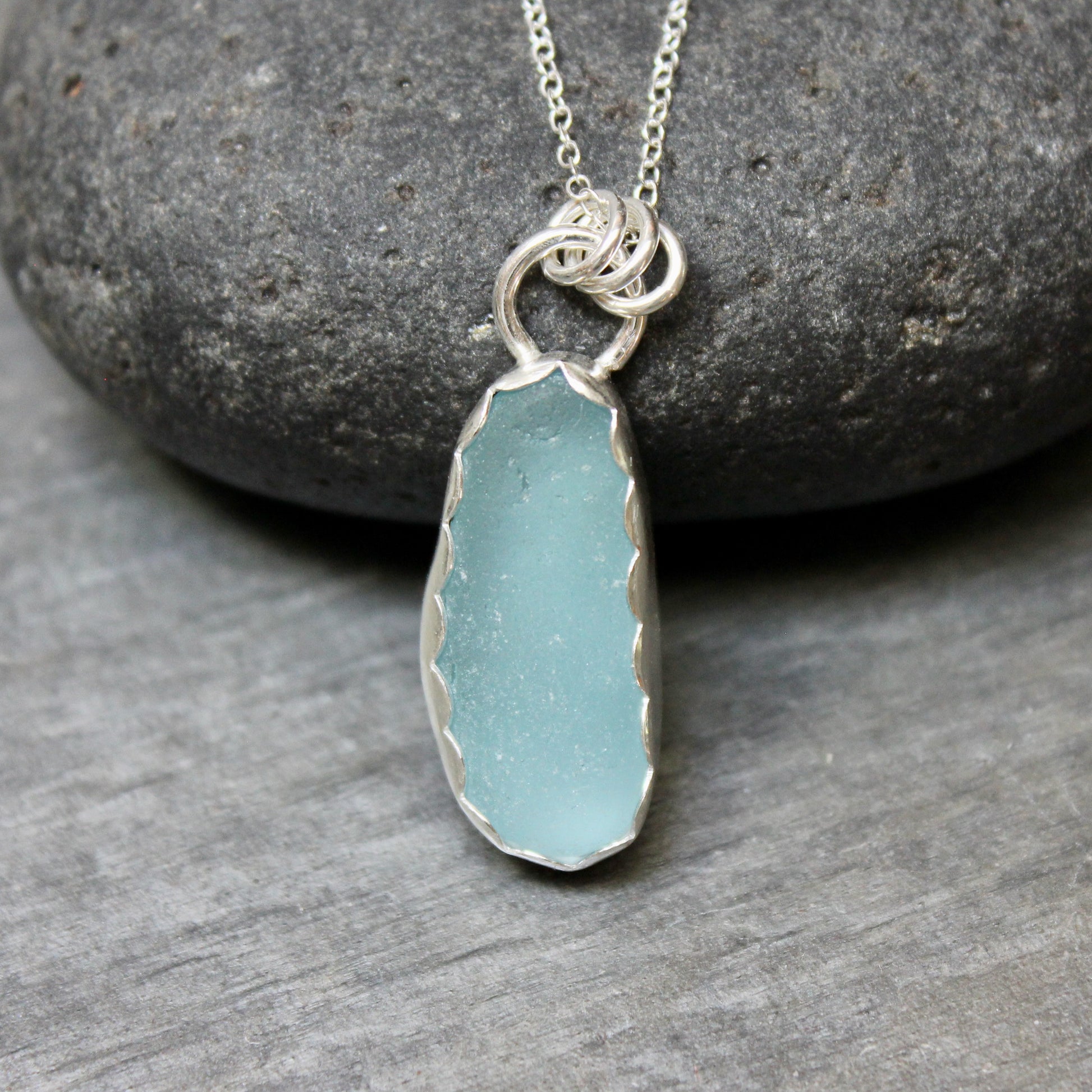 Necklace with a light blue sea glass on a stone surface