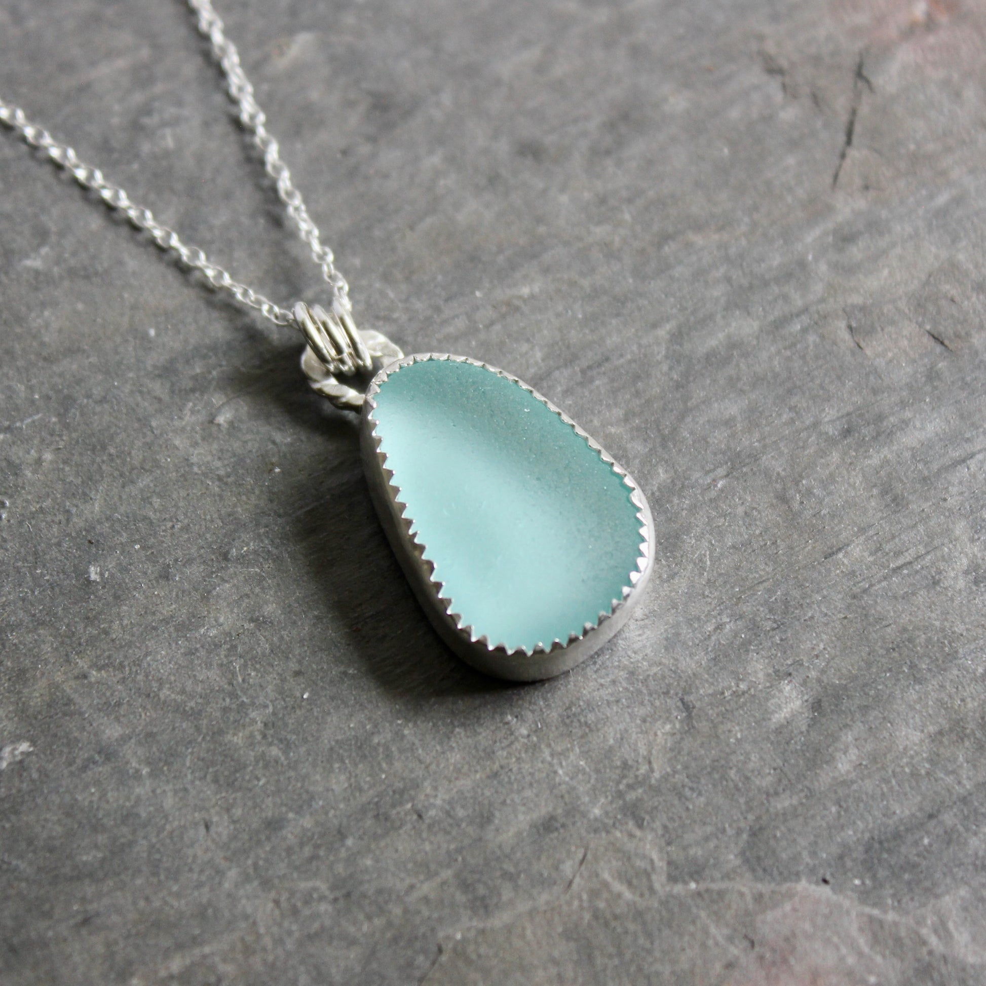 Teal Sea Glass necklace on a gray stone surface