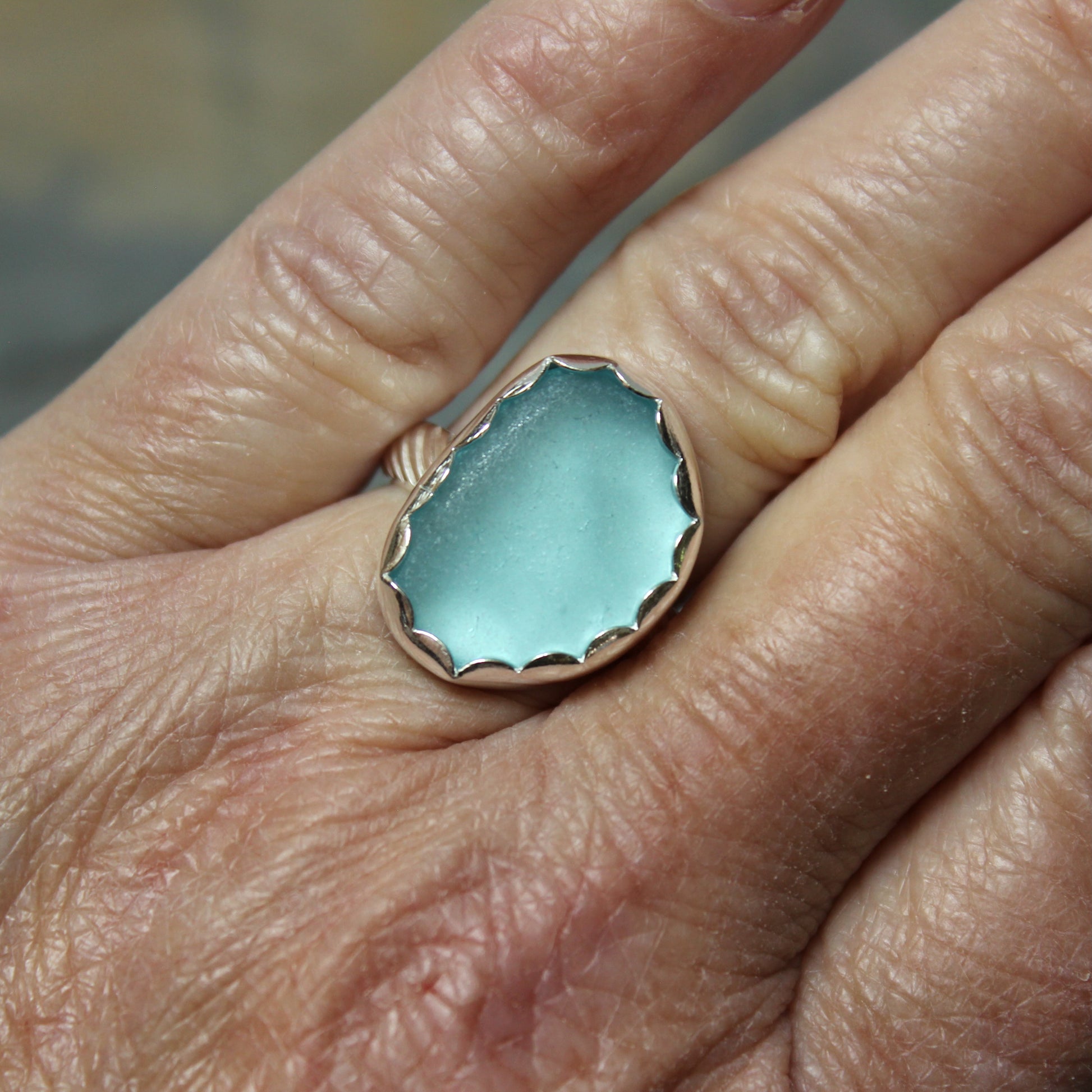 Aqua Sea Glass ring with silver band on a hand.
