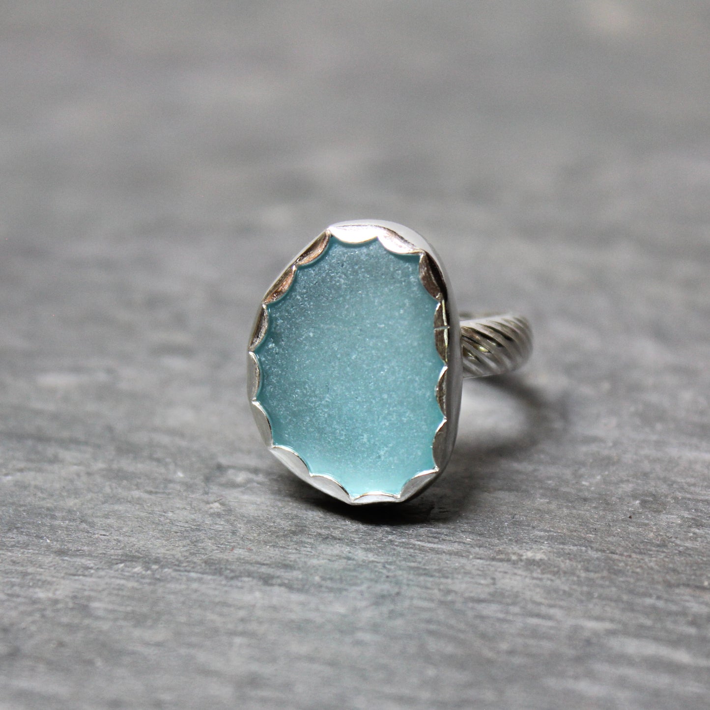 Aqua Sea Glass ring with silver band on a gray background