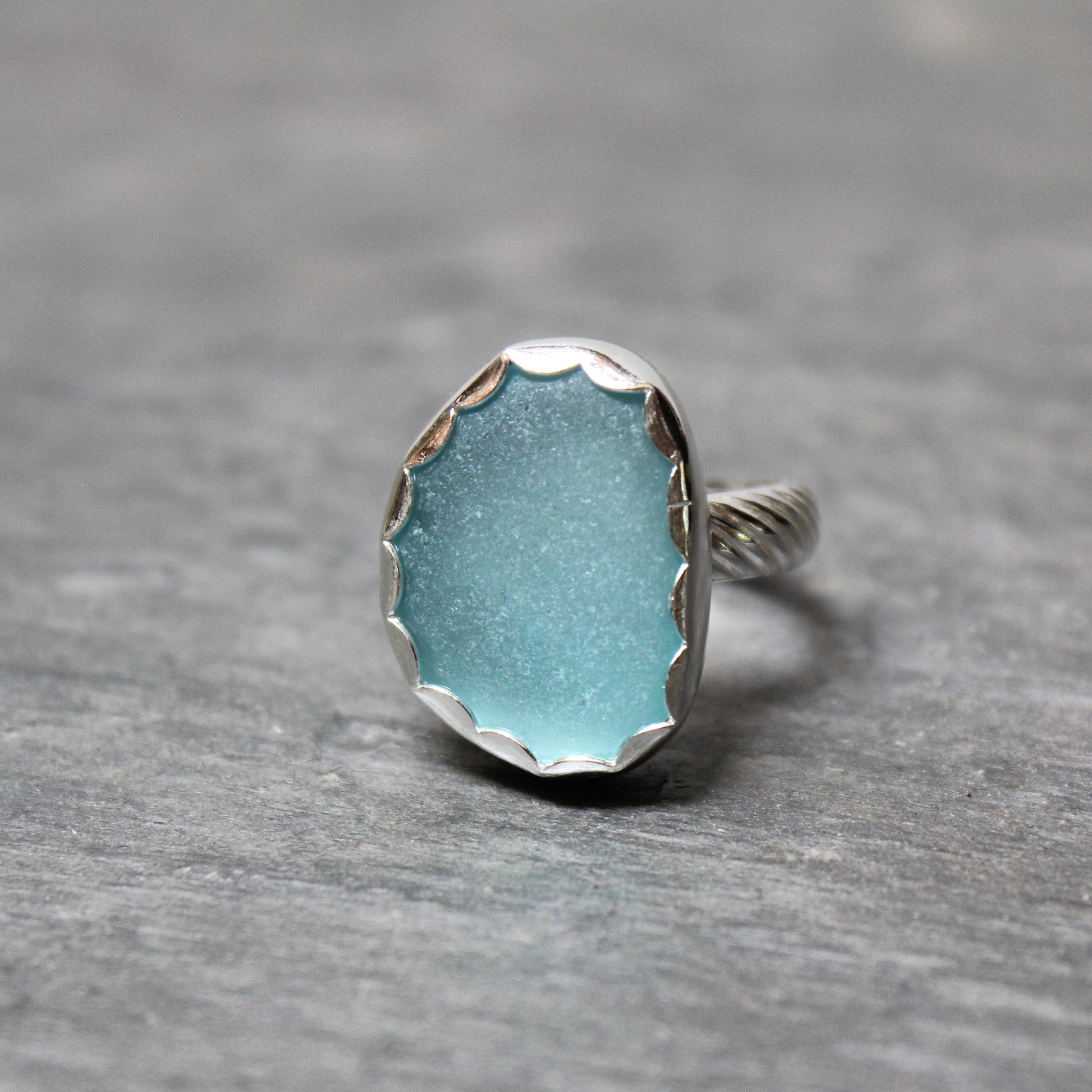 Aqua Sea Glass ring with silver band on a gray background