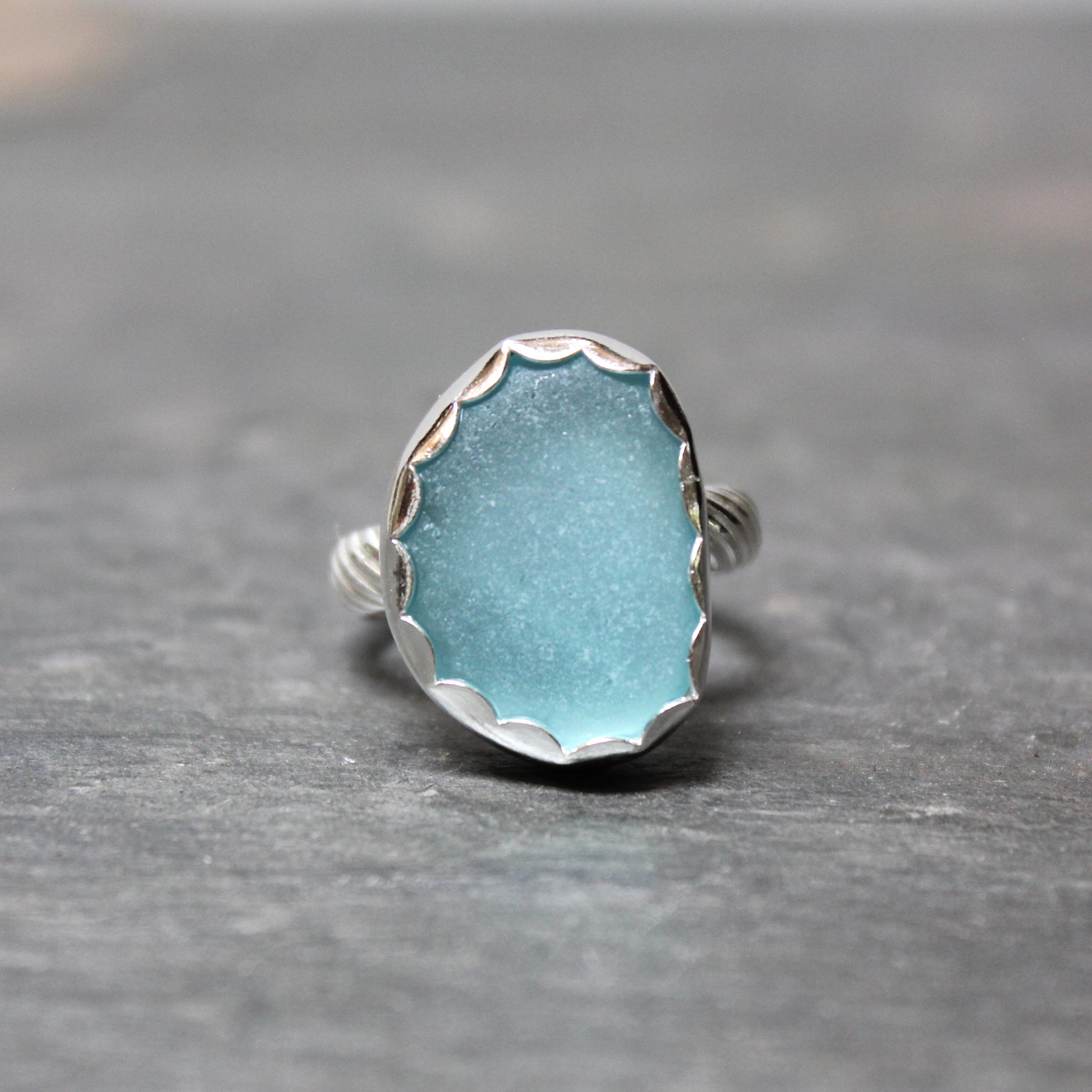 Aqua Sea Glass ring with silver band on a gray background