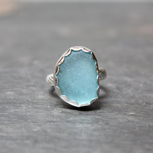 Aqua Sea Glass ring with silver band on a gray background