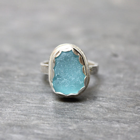 Turquoise sea glass ring with silver setting on a gray stone