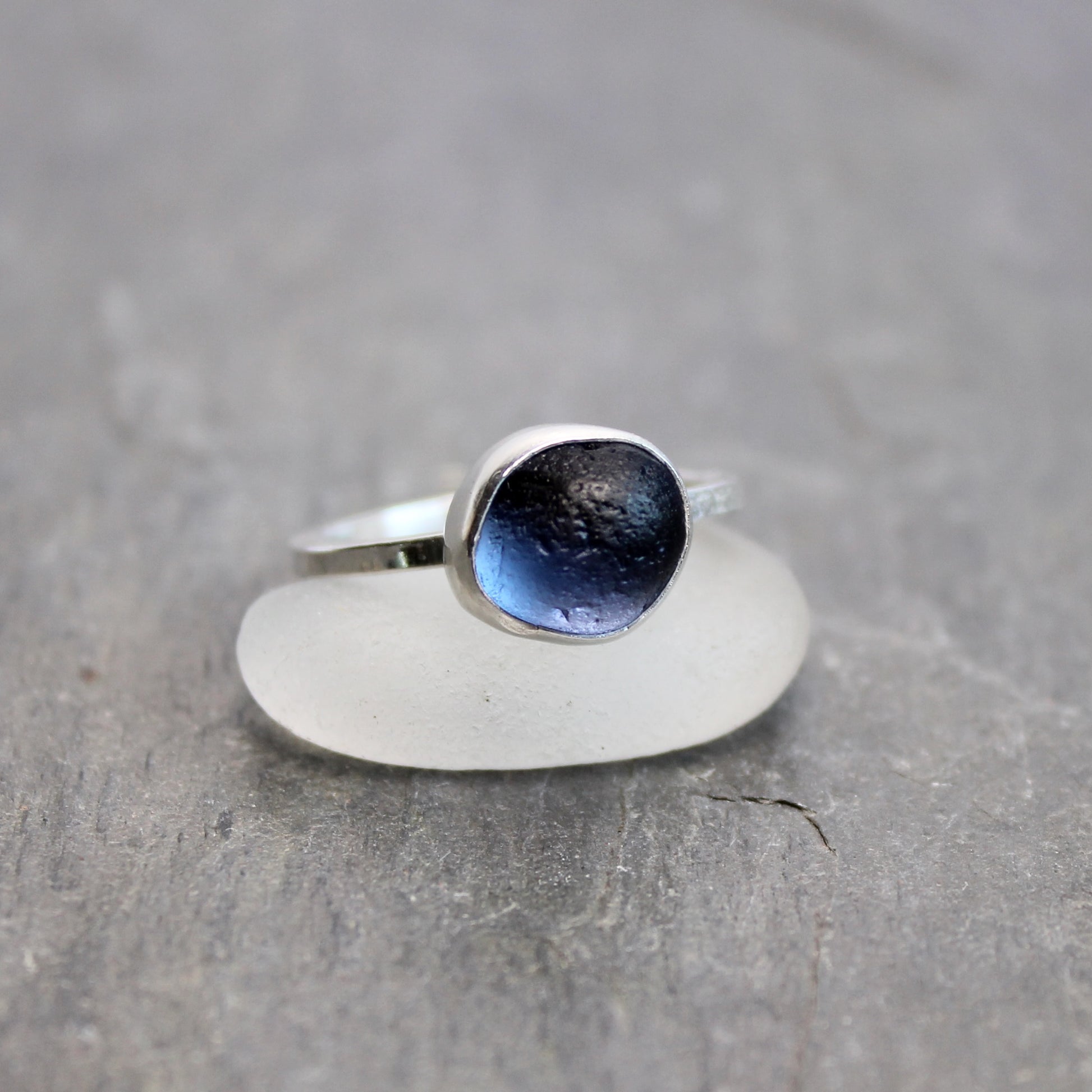 Silver ring with a blue gemstone on a gray surface