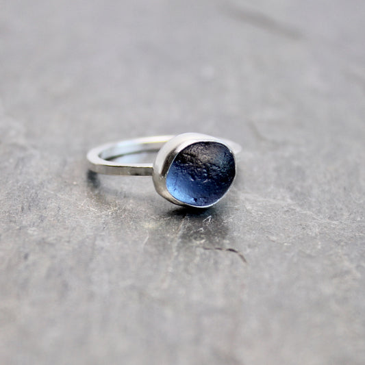 Silver ring with blue sea glass on a gray surface