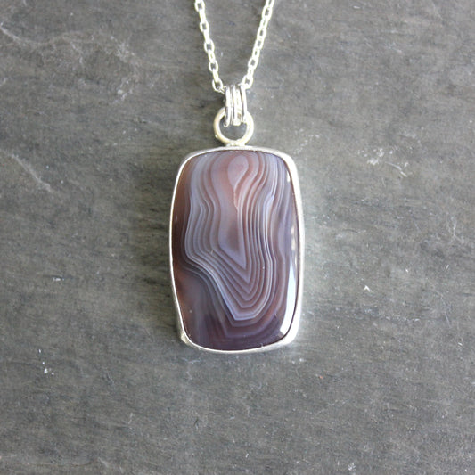 Necklace with a pendant featuring a rectangular botswana agate on a gray background